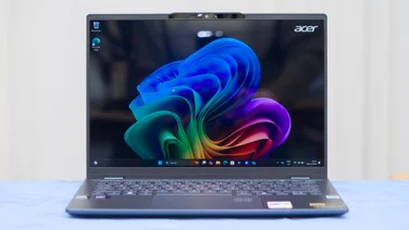 The Acer Swift 14 AI OLED (SF14-51) pictured, open, from the front on a blue surface